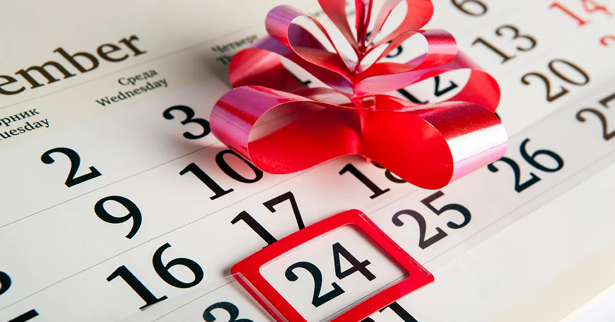 Ein Kalender, in dem der 24. Dezember markiert ist. Auf dem Kalender liegt eine rote Schleife.